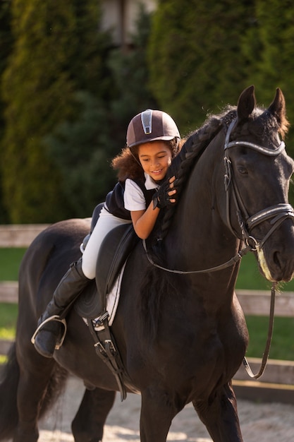 Niño de tiro completo aprendiendo a montar a caballo