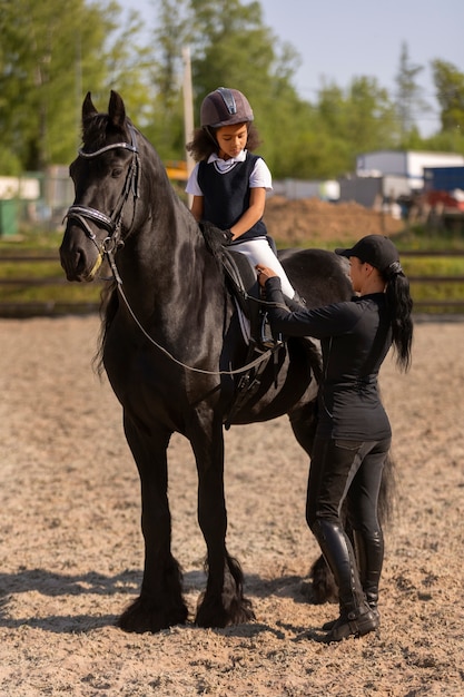 Foto gratuita niño de tiro completo aprendiendo a montar a caballo