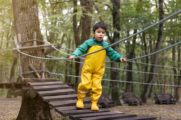 Niño de tiro completo caminando sobre el puente de madera