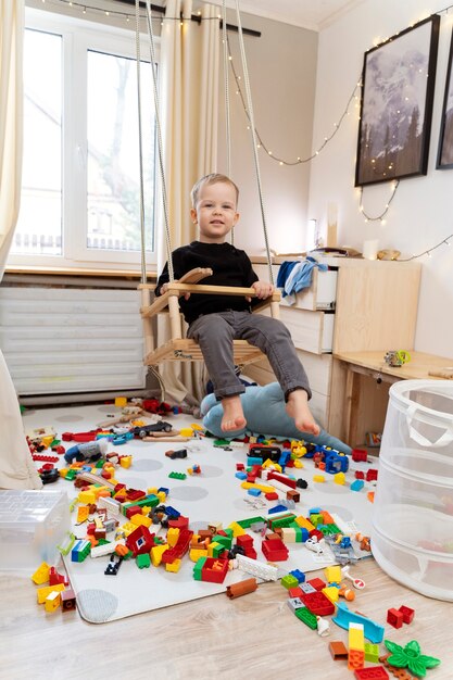 Niño de tiro completo en columpio en casa.