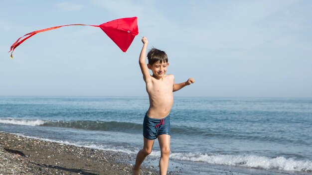 Niño de tiro completo corriendo en la playa