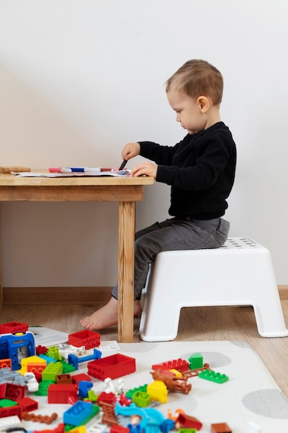 Niño de tiro completo dibujando en la mesa