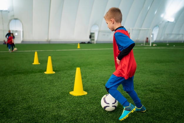 Niño de tiro completo entrenando en fútbol.