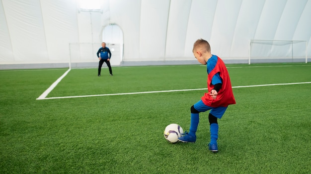 Niño de tiro completo entrenando con pelota