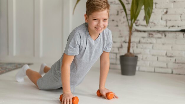 Niño de tiro completo haciendo ejercicio en el interior