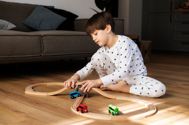 Foto gratuita niño de tiro completo jugando con carros de madera.