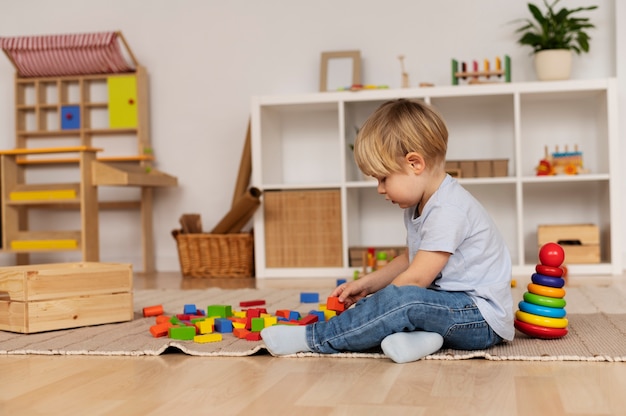 Foto gratuita niño de tiro completo jugando con un juguete en casa