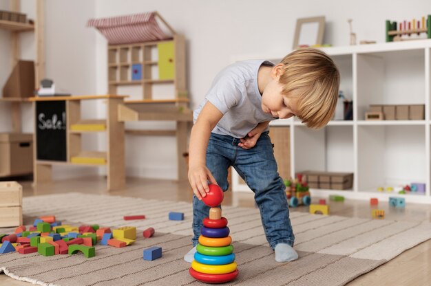 Niño de tiro completo jugando en el piso con juguete de madera