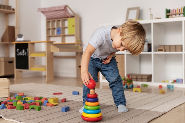 Niño de tiro completo jugando en el piso con juguete de madera