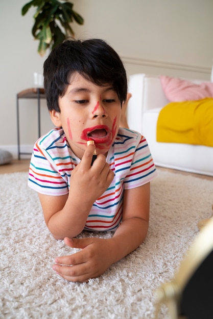 Niño de tiro completo con lápiz labial rojo