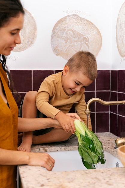 Foto gratuita niño de tiro completo lavando lechuga