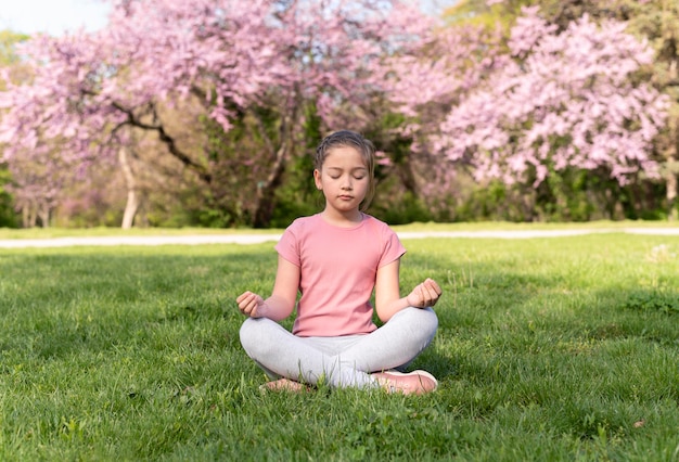 Niño de tiro completo meditando sobre la hierba