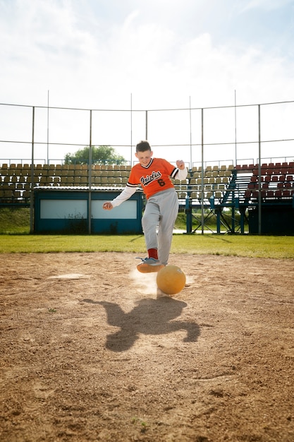 Foto gratuita niño de tiro completo pateando la pelota amarilla