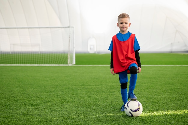 Foto gratuita niño de tiro completo con pelota en el campo