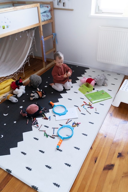 Niño de tiro completo en el piso con juguetes