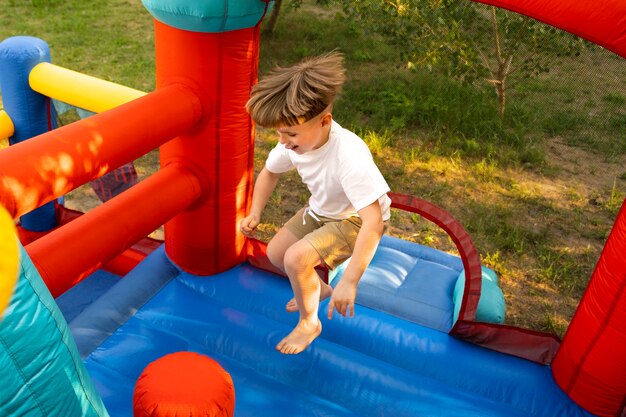 Niño de tiro completo saltando en casa de rebote