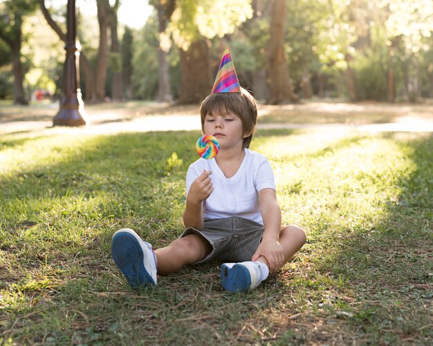 Niño de tiro completo sentado en el césped