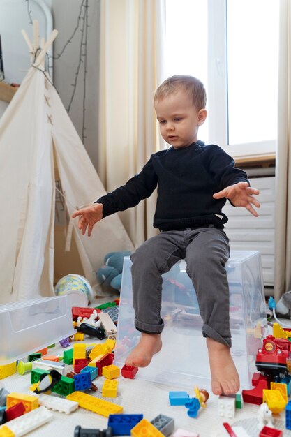 Niño de tiro completo sentado en un contenedor