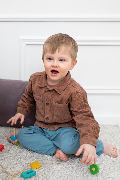 Foto gratuita niño de tiro completo sentado en el piso