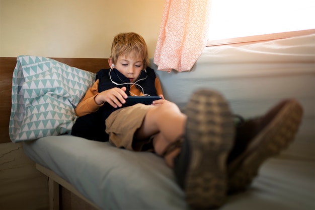 Foto gratuita niño de tiro completo con teléfono inteligente