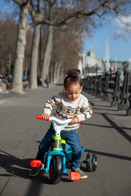 Niño de tiro completo en triciclo al aire libre