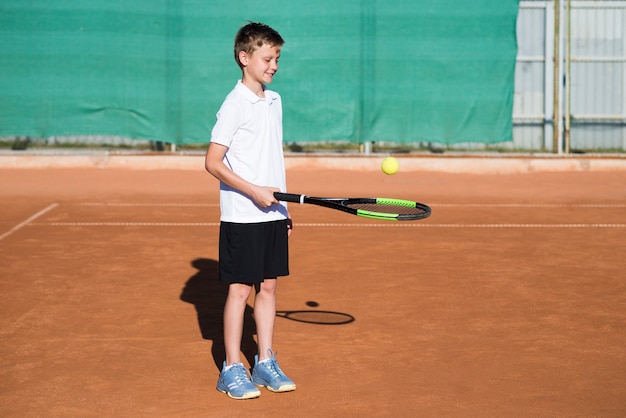Niño tiro largo jugando tenis