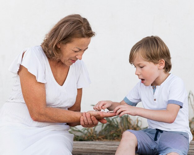 Niño de tiro medio y abuela con conchas.