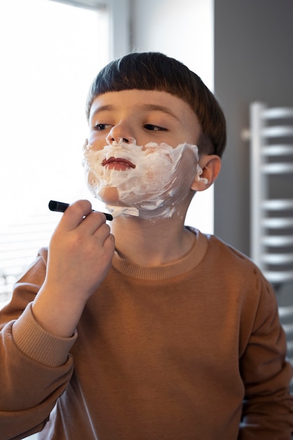 Niño de tiro medio aprendiendo a afeitarse