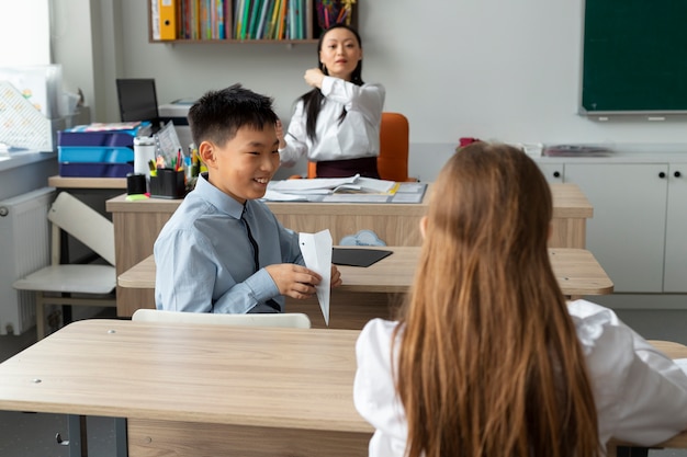 Niño de tiro medio con avión de papel en la escuela.