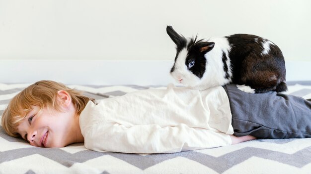 Niño de tiro medio en la cama con conejo