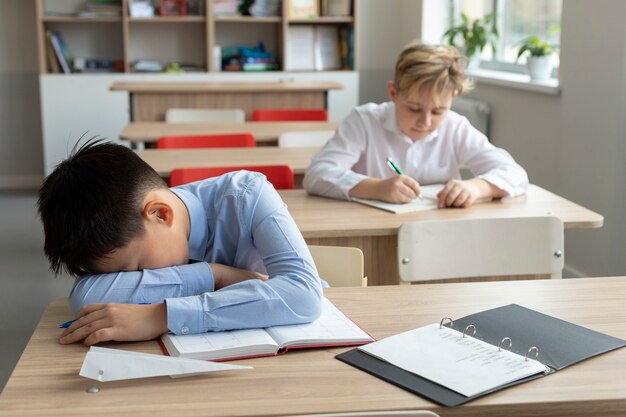 Niño de tiro medio durmiendo en la escuela