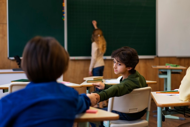 Foto gratuita niño de tiro medio escribiendo a bordo