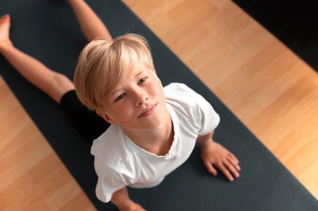 Niño de tiro medio en estera de yoga