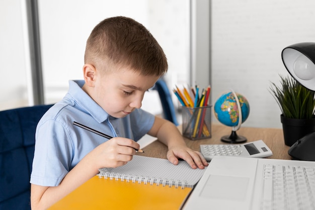 Foto gratuita niño de tiro medio estudiando en casa