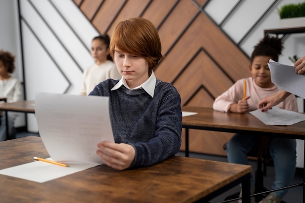 Niño de tiro medio haciendo trampa en el examen escolar