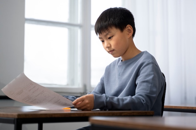 Niño de tiro medio haciendo trampa en el examen escolar