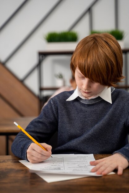 Niño de tiro medio haciendo trampa en el examen escolar