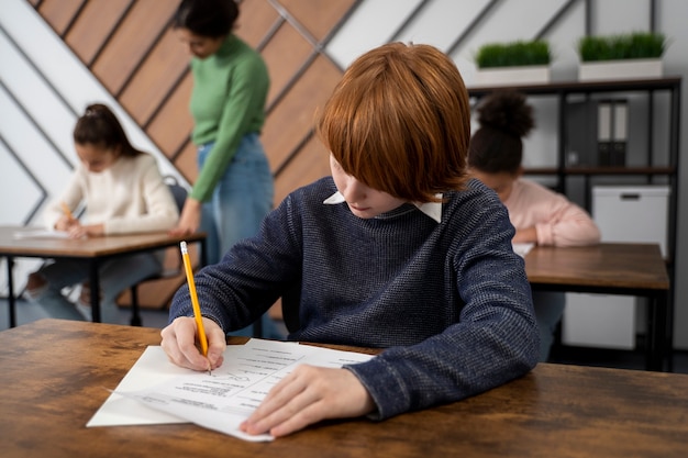 Niño de tiro medio haciendo trampa en el examen escolar