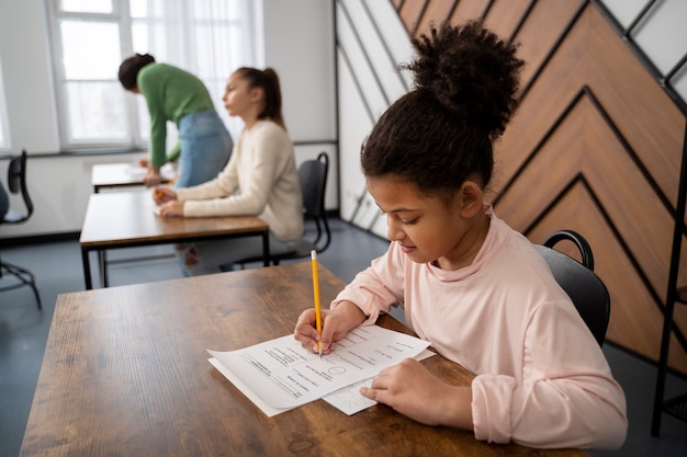 Foto gratuita niño de tiro medio haciendo trampa en el examen escolar