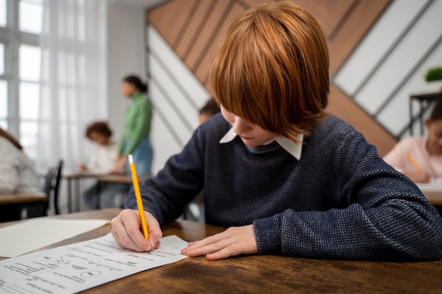 Foto gratuita niño de tiro medio haciendo trampa en el examen escolar