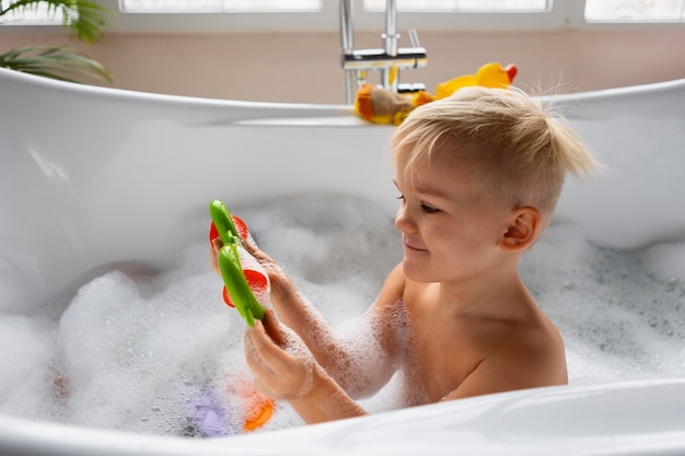 Foto gratuita niño de tiro medio jugando en la bañera