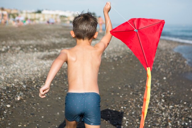 Niño de tiro medio jugando con cometa