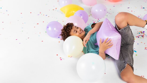 Niño de tiro medio jugando con globos