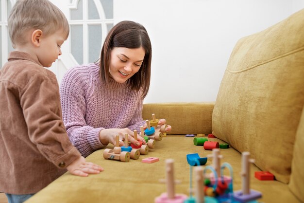 Niño de tiro medio y madre jugando con madera.