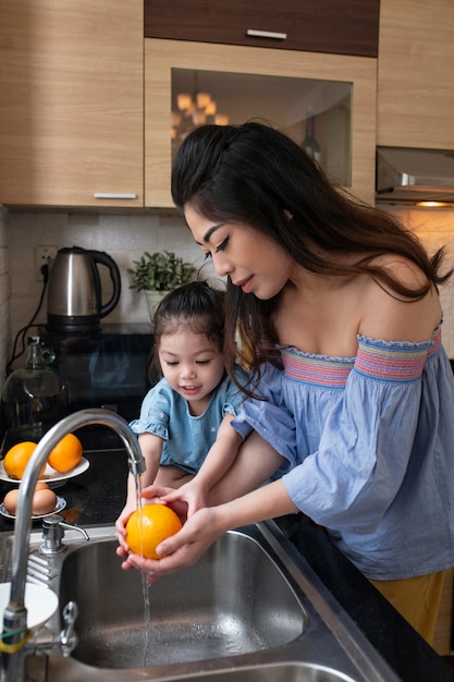 Foto gratuita niño de tiro medio y madre lavando naranja