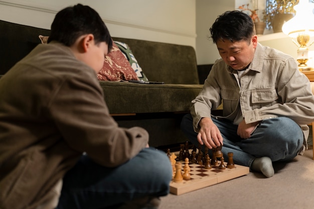 Niño de tiro medio y padre jugando al ajedrez.