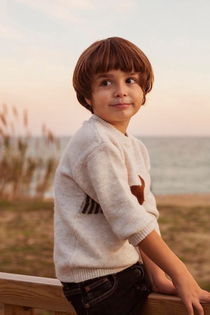 Foto gratuita niño de tiro medio sentado en la valla