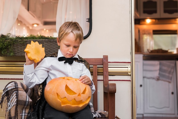 Niño de tiro medio sosteniendo calabaza tallada