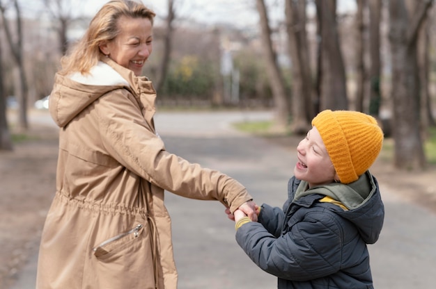 Niño de tiro medio sosteniendo la mano de la mujer