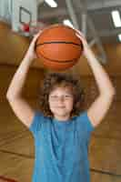 Foto gratuita niño de tiro medio sosteniendo la pelota de baloncesto